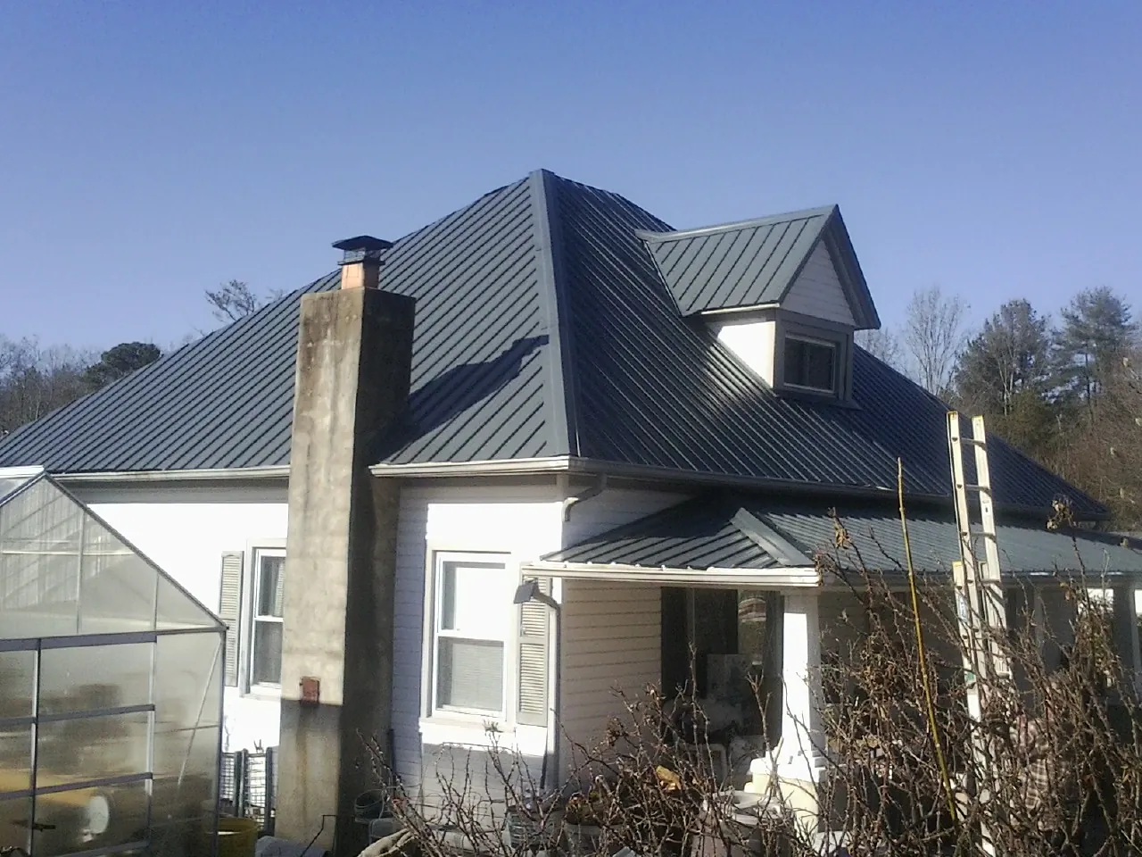 Dark blue standing seam metal roof on a white farmhouse with dormer — Slate & Tile Roof Repair by Roofing Brothers in Yorkville