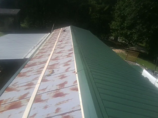 Old rusted panels beside newly installed green metal roofing — Wind Damage Roof Repair by Roofing Brothers in Yorkville